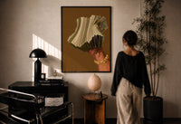 Hand Holding Fanned Cash print in a black frame on a sunlit plaster wall, a woman looking on beside a mushroom lamp