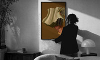 Hand Holding Fanned Cash print in a slim black frame being hung on a sunlit wall in a monochrome room
