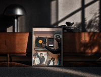 Black-framed Hand on a Wooden Record Player print on the floor in front of a dark wooden console