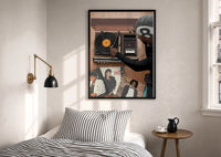Hand on a Wooden Record Player print in a black frame above a bed with striped linens, a brass wall lamp and a sunlit window