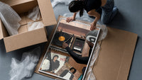 Hand on a Wooden Record Player framed print being unpacked from protective bubble wrap and a box