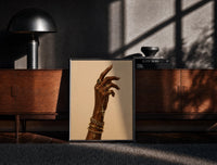 Black-framed Hand with a Cross and Gold Chains print on the floor in front of a dark wooden console