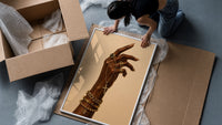 Hand with a Cross and Gold Chains framed print being unpacked from protective bubble wrap and a box