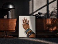 Black-framed Hand with Blue Bangles print on the floor in front of a dark wooden console