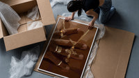 Gold Cross Necklace framed print being unpacked from protective bubble wrap and a box