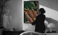 Green French Tips print in a slim black frame being hung on a sunlit wall in a monochrome room