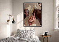 Heart Nail Designs print in a black frame above a bed with striped linens, a brass wall lamp and a sunlit window