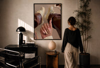 Heart Nail Designs print in a black frame on a sunlit plaster wall, a woman looking on beside a mushroom lamp
