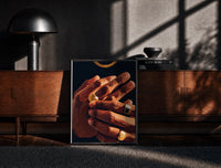Black-framed Hands with Gold Rings print on the floor in front of a dark wooden console
