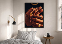 Hands with Gold Rings print in a black frame above a bed with striped linens, a brass wall lamp and a sunlit window