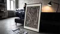 Nude witches with cauldron flying goat print in a slim black frame leaning on a dark sofa in a concrete print studio