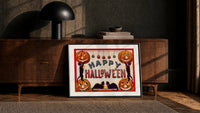 Halloween jack-o-lanterns and black cats print in a black frame leaning against a walnut console in lamplight