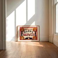 Halloween jack-o-lanterns and black cats print in an oak frame on a sunlit wood floor beneath tall window light