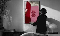 Healing Is a Journey Book Page print in a slim black frame being hung on a sunlit wall in a monochrome room