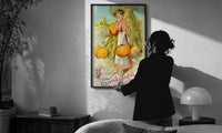 Pumpkin Girl Hearty Greeting print in a slim black frame being hung on a sunlit wall in a monochrome room