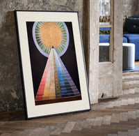 Golden sun with pyramid of colors print in a black frame leaning beside a vintage door on parquet