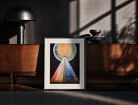 Black-framed Golden sun with pyramid of colors print on a moody console with designer coffee-table books