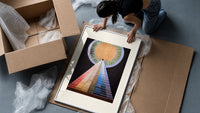 Golden sun with pyramid of colors framed print being unpacked from protective bubble wrap and a box