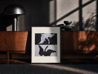 Black-framed Two swans, one white one black print on a moody console with designer coffee-table books