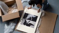 Two swans, one white one black framed print being unpacked from protective bubble wrap and a box