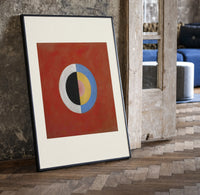 Divided circle with concentric rings print in a black frame leaning beside a vintage door on parquet