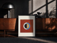 Black-framed Divided circle with concentric rings print on a moody console with designer coffee-table books