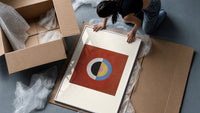 Divided circle with concentric rings framed print being unpacked from protective bubble wrap and a box