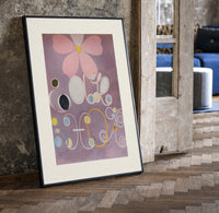 Abstract flower with swirls and circles print in a black frame leaning beside a vintage door on parquet
