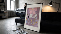 Abstract flower with swirls and circles print in a slim black frame leaning on a dark sofa in a concrete print studio