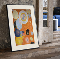 Abstract spirals and snail shells print in a black frame leaning beside a vintage door on parquet