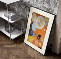 Abstract spirals and snail shells poster in a black frame leaning beside a shelf in a raw-plaster loft