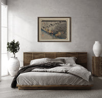 Travelers in rainstorm on hillside path print in a dark wood frame above a rattan bed on a plaster wall