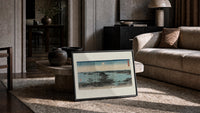 Japanese bay landscape with moon print in a slim black frame leaning on a travertine coffee table