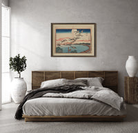 Flock of geese flying over bay print in a dark wood frame above a rattan bed on a plaster wall
