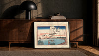 Flock of geese flying over bay print in a black frame leaning against a walnut console in lamplight