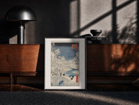 Black-framed Snowy bridge with travelers in winter print on a moody console with designer coffee-table books