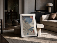 Snowy bridge with travelers in winter print in a black frame leaning on a travertine table in a sunlit lounge
