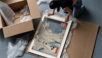 Snowy bridge with travelers in winter framed print being unpacked from protective bubble wrap and a box
