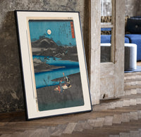 Women washing cloth by moonlit river print in a black frame leaning beside a vintage door on parquet