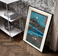 Women washing cloth by moonlit river poster in a black frame leaning beside a shelf in a raw-plaster loft