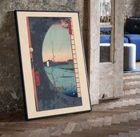 River landscape with plum blossom branch print in a black frame leaning beside a vintage door on parquet