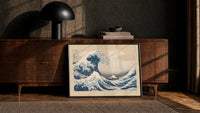 Great wave with boats and Mount Fuji print in a black frame leaning against a walnut console in lamplight