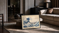 Great wave with boats and Mount Fuji print in a slim black frame leaning on a travertine coffee table