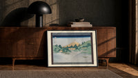 Mount Fuji reflected in water print in a black frame leaning against a walnut console in lamplight