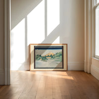 Mount Fuji reflected in water print in an oak frame on a sunlit wood floor beneath tall window light