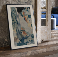 Japanese waterfall with travelers and hut print in a black frame leaning beside a vintage door on parquet