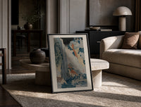 Japanese waterfall with travelers and hut print in a black frame leaning on a travertine table in a sunlit lounge