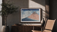 Mount Fuji with snow-capped peak print in a wood frame above a fluted sideboard beside an olive tree