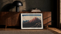Mount Fuji with lightning storm print in a black frame leaning against a walnut console in lamplight