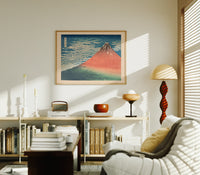 Red Mount Fuji with clouds print in an oak frame above a mid-century book console with a vintage radio